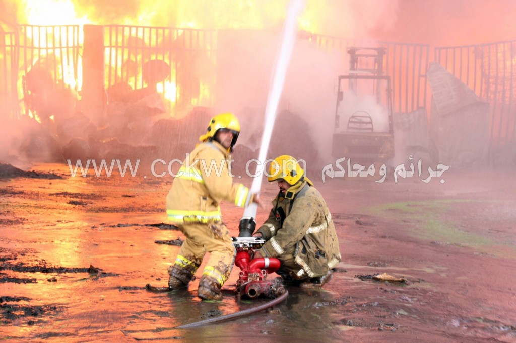 رجلا إطفاء يجتهدان في مكافحة النيران من إحدى النواحي